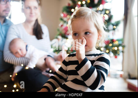 Parents with children at Christmas tree, girl picking her nose. Stock Photo