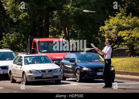 Germany,  Cologne, juggler in front of cars, waiting at traffic lights, after the performance he asks the drivers for a donation. Stock Photo