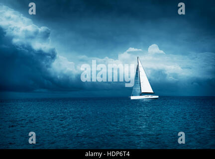 White Yacht Sailing in Stormy Sea. Dark Photo. Stock Photo