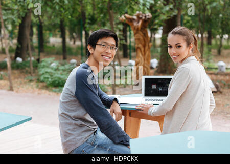 Happy beautiful young couple sitting and using laptop together Stock Photo
