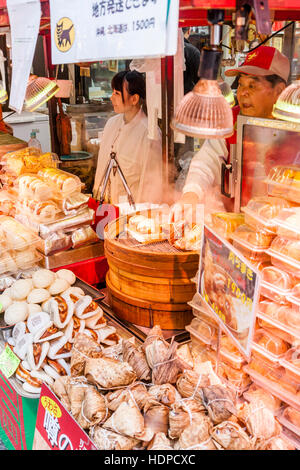 Japan, Kobe, Nankinmachi, Chinatown. Chinese food stall counter, Pork Belly buns being steamed in wooden bowl. Other foods packed on counter. Stock Photo