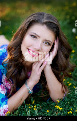 beautiful happy woman lying on the grass with yellow flowers Stock Photo