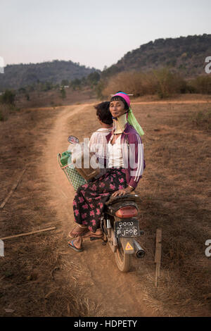 A Kayan woman riding on a motorbike in a dirt road, Kayah State, Myanmar. Stock Photo