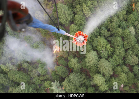 U.S. National Guard soldiers douse a Shasta County wildfire with water from Bambi bucket attached to a Boeing CH-47 Chinook heavy-lift helicopter August 18, 2015 in Redding, California. Stock Photo