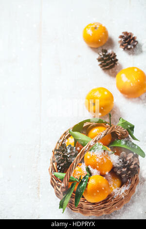 Composition with Tangerines and Pine Cones in a basket on Wooden Background Stock Photo