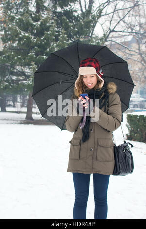 woman writing text message in snow covered park Stock Photo