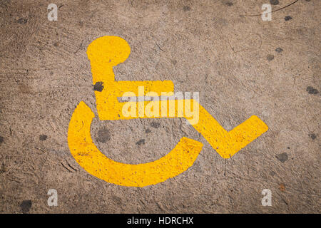 Yellow disabled sign on pathway near lowered kerb Stock Photo