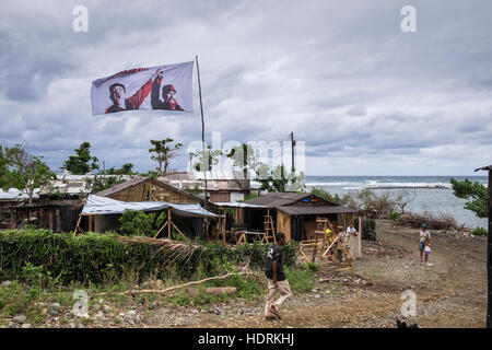 Flag with Fidel and Raul Castro flying over area affected by hurricane Mathew procliaiming, Venceremos, we will win, Baracoa, Cuba Stock Photo