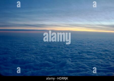 The view from outside the airplane window above clouds during winter and sunset. Stock Photo