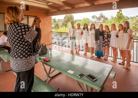 Wearing white formal dresses, multiracial teen girls and their mothers pose at a Laguna Niguel, CA, Catholic church before their Confirmation mass. Stock Photo