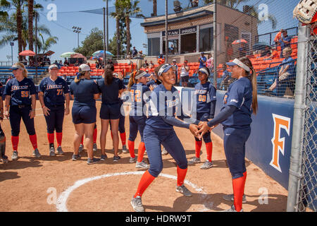 Multiracial college women's softball players prepare for a game on the field in Fullerton, CA. Stock Photo