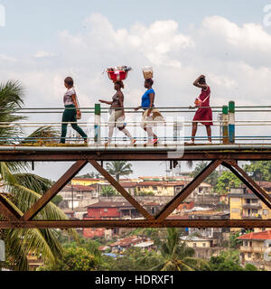 Women crossing old Freetown railway bridge, Tengbeh Bridge, carrying goods on head