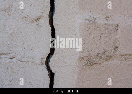 A large vertical crack in a painted brick wall Stock Photo