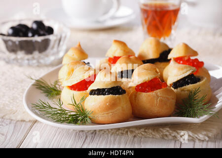 profiteroles stuffed with red and black caviar on a plate close-up. horizontal Stock Photo