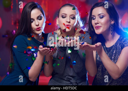 Beautiful women blowing confetti in front of camera Stock Photo