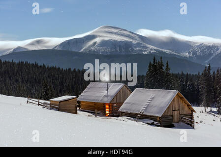 Fantastic night landscape glowing by moon light. Dramatic wintry scene with snowy house. Carpathians, Ukraine, Europe. Stock Photo
