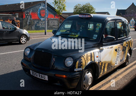 Belfast Black Taxi tours in front of one of the loyalist murals at the bottom of the Newtownards Road in East Belfast, Northern Ireland, UK. U.F.F. Mu Stock Photo