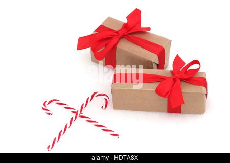 Christmas presents with red bows and ribbons next to candy canes against a white background Stock Photo