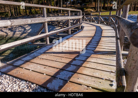 Wooden bridge twisting to the left with some frost in the shadows. Close-up view. Stock Photo