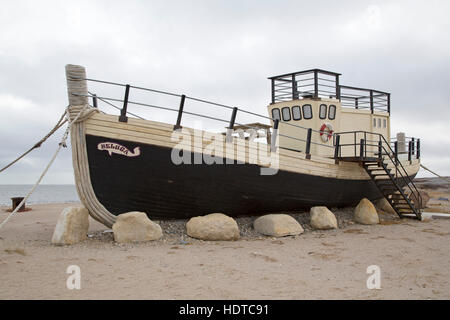 The Beluga, a boat by the shore of the Hudson Bay, at Churchill in Manitoba, Canada. The boat stands on sand by the shoreline. Stock Photo