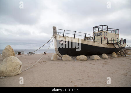 The Beluga, a boat by the shore of the Hudson Bay, at Churchill in Manitoba, Canada. The boat stands on sand by the shoreline. Stock Photo