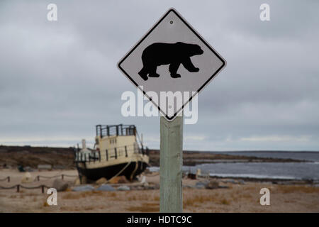 The Beluga, a boat by the shore of the Hudson Bay, at Churchill in Manitoba, Canada. A warning sign for polar bears stands close to the boat. Stock Photo