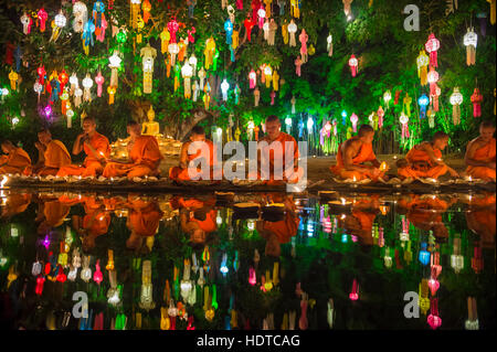 CHIANG MAI, THAILAND - NOVEMBER 06, 2014: Young Buddhist monks sit meditating at a festival of lights loi krathong ceremony.