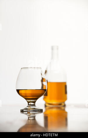 Cognac in glass with bottle on white background Stock Photo