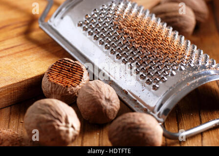 nutmeg and grater on wooden chopping board Stock Photo