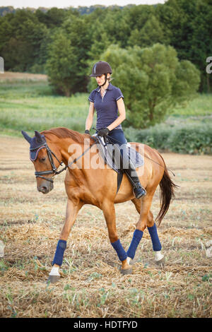 woman riding on brown horse wearing helmet Stock Photo