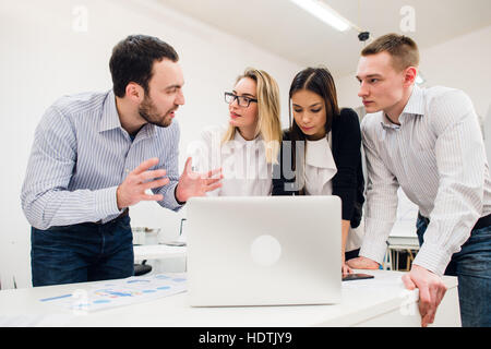 Colleagues at an office meeting talking and working on a laptop Stock Photo
