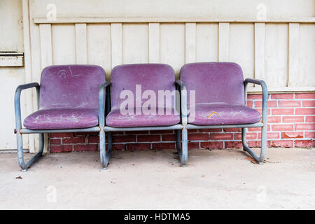 Old weathered, cracked purple leather chairs sitting outside of a building. USA. Stock Photo