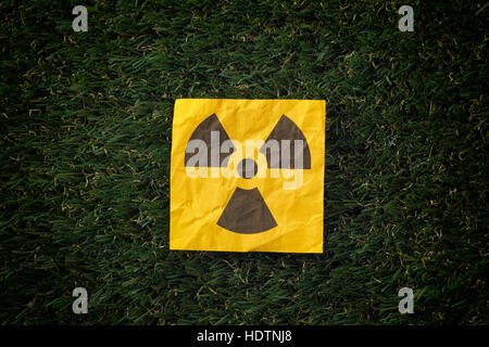 Radiation warning sign on a green grass. Close up.