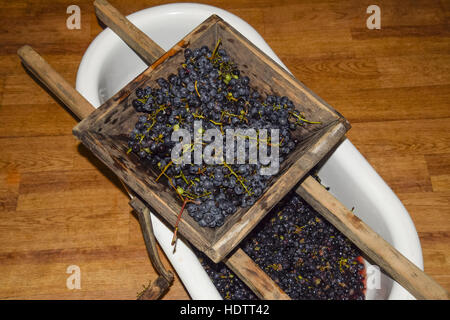 Manual mechanism for crushing grapes. Crush the grapes into juice and wine. Stock Photo