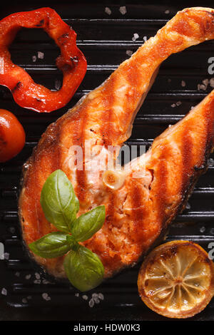 Grilled red fish steak salmon and vegetables on the grill pan. vertical top view close-up Stock Photo