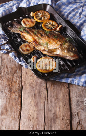 fried carp with lemon, onion and spices on the grill pan, horizontal Stock Photo