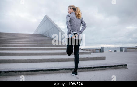 Full length rear view of young female stretching her leg before a run. fitness woman stretching before jogging. Stock Photo