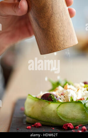 close up of hand with salt shaker salting salad Stock Photo