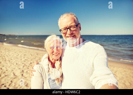 seniors taking picture with selfie stick on beach Stock Photo