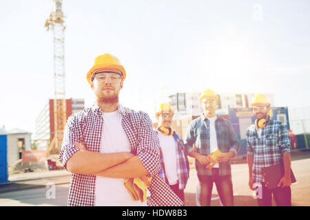 group of smiling builders in hardhats outdoors Stock Photo