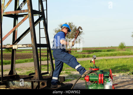 worker with pipe wrench on oilfield pipeline Stock Photo