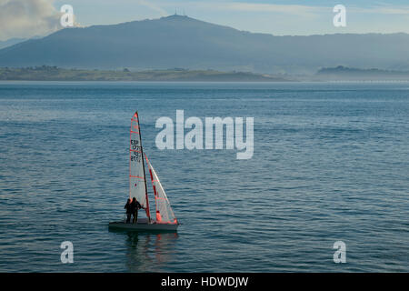 Sailing boats in the afternoon on Santander bay. In the background, the town of Pedreña and the mountain of the Cantabrian range Stock Photo