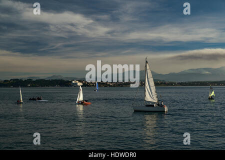 Sailing boats in the afternoon on Santander bay. In the background, the town of Pedreña and the mountain of the Cantabrian range Stock Photo
