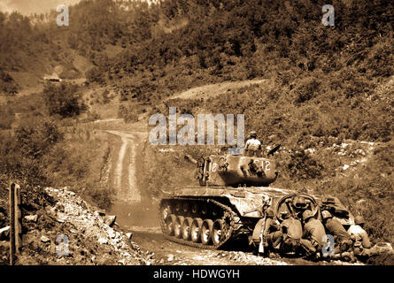 Marine infantrymen take cover behind a tank while it fires on Communist troops ahead.  Hongchon Area, May 22, 1951. Stock Photo