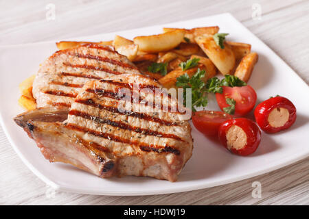 Grilled pork steak with potatoes and vegetables on a plate close-up. horizontal Stock Photo