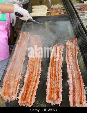 long strip of meat cooked on the hot plate in the stand of street foods Stock Photo