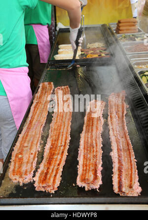 long strip of meat cooked on the hot plate in the stand that prepares food on the road Stock Photo