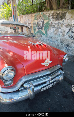 Cuban classic American car with revolutionary graffiti on wall Stock Photo