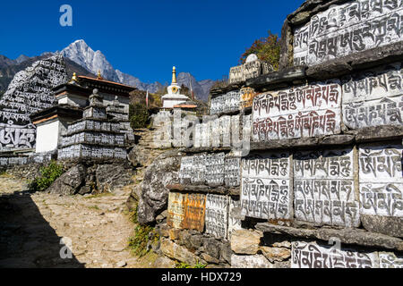 Many mani stones are build into a wall at the entrance of the village. Stock Photo