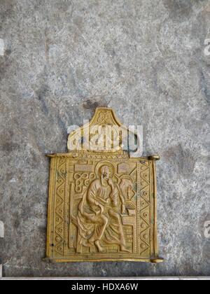 Vintage ancient metal bronze, copper orthodox icon scapular covered with green patina on an old stone background. Stock Photo